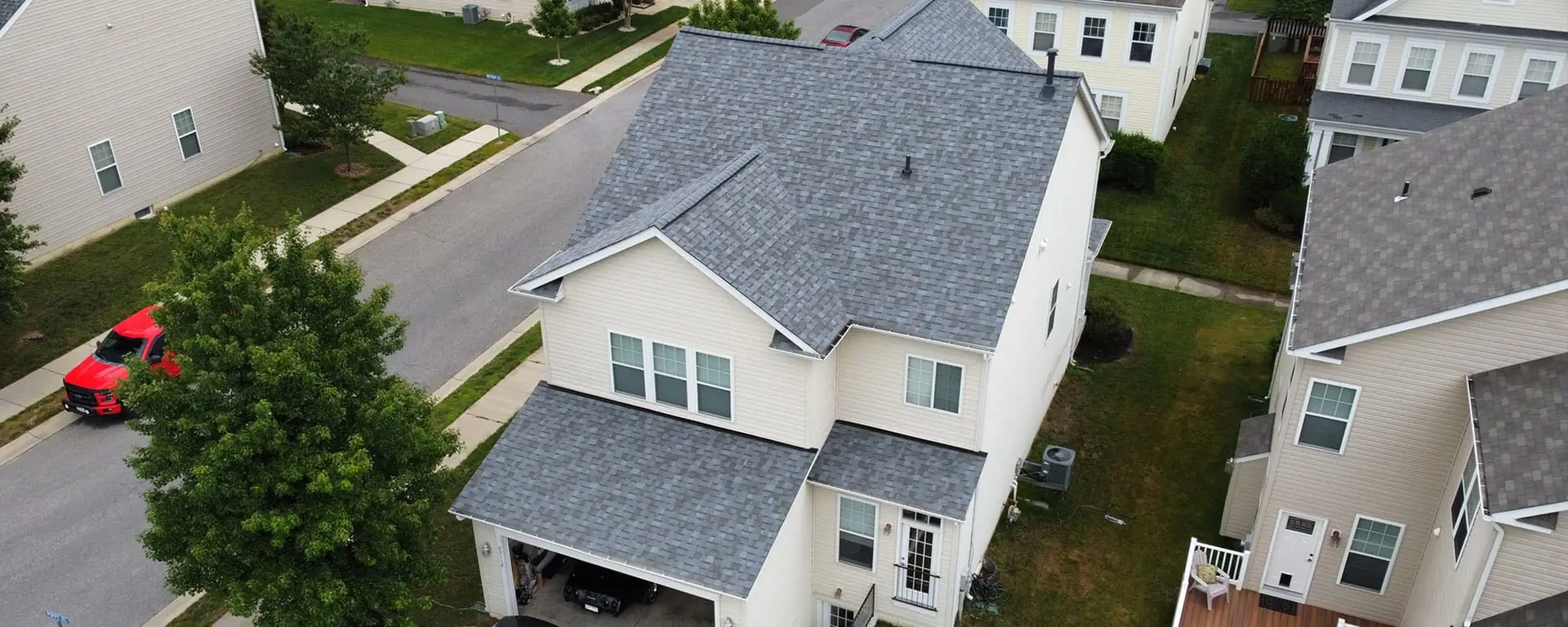 JDH Remodeling aerial view of a completed asphalt shingle roof installation on a modern two-story Dunkirk Maryland home with white trim