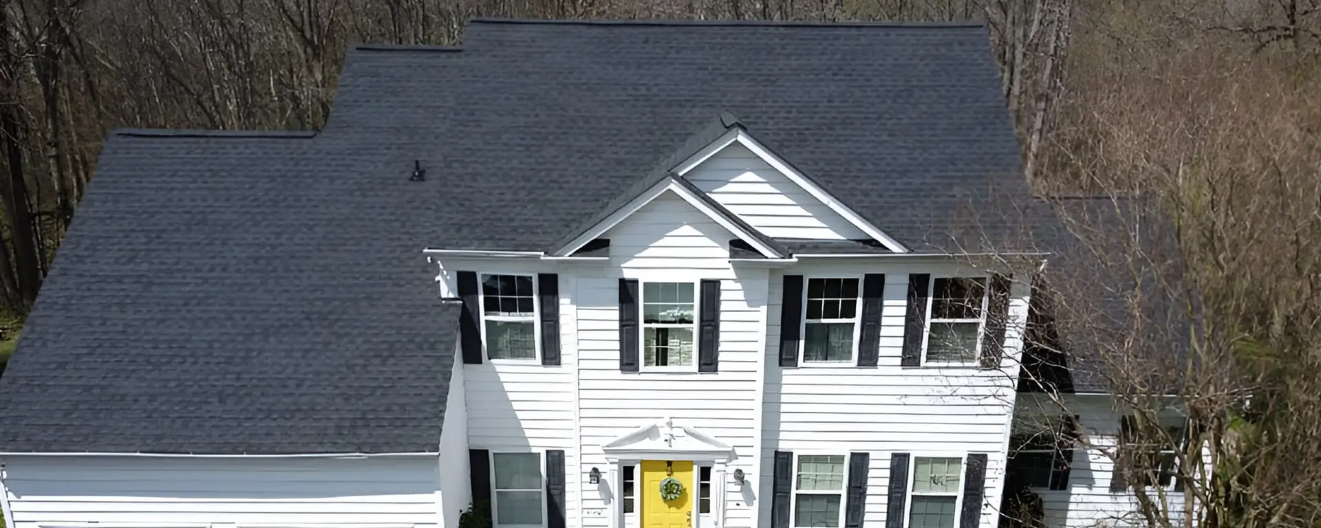 JDH Remodeling completed two-story colonial home in Lusby Maryland with newly installed dark gray asphalt shingle roof and white siding exterior