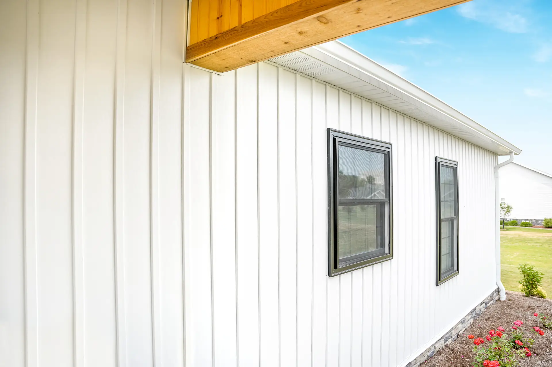 JDH Remodeling clean white board-and-batten siding with black-framed windows and wooden soffit overhang on a modern Huntingtown Maryland home
