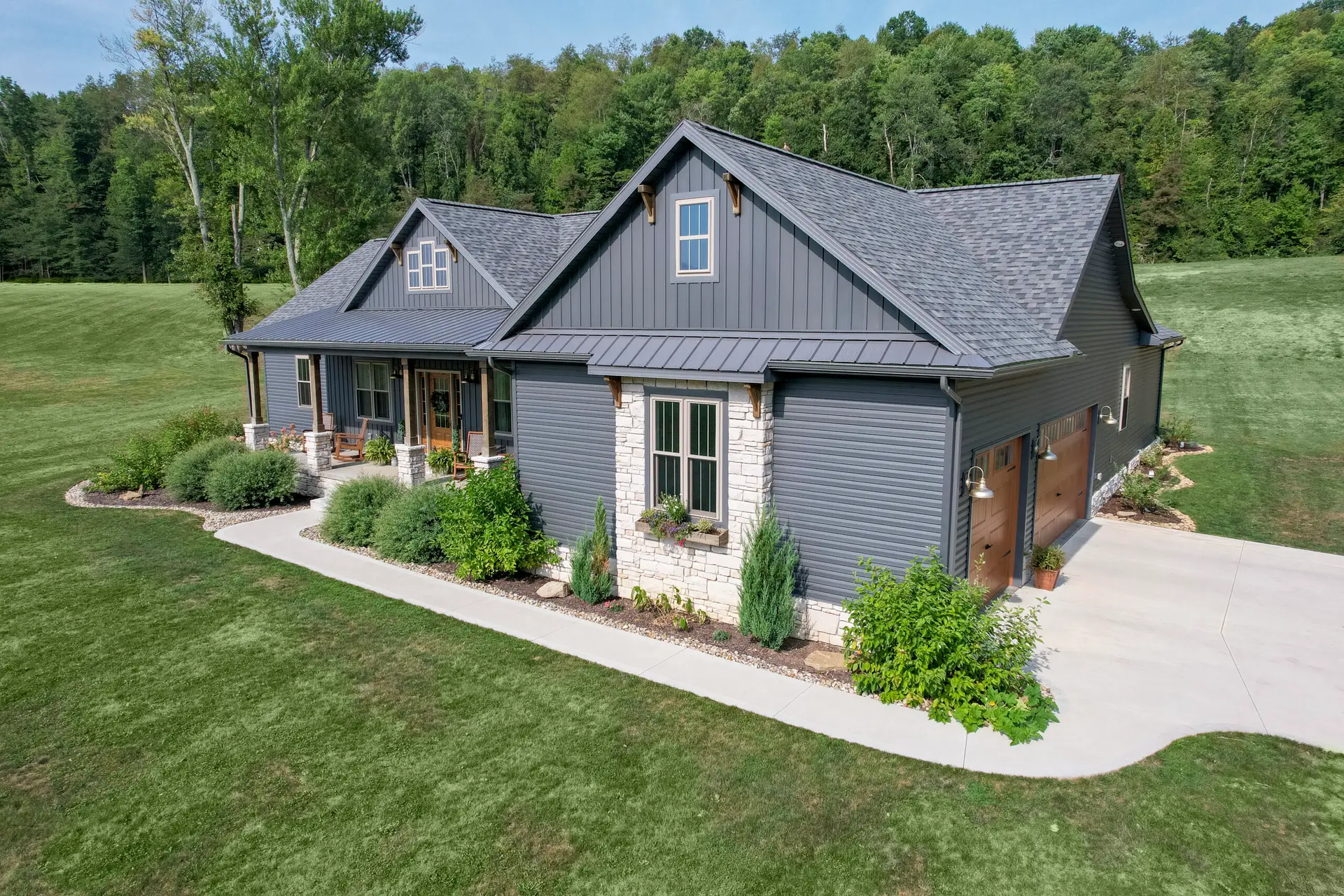 Lusby MD Roofing Contractor: Calvert Cliffs, Cove Point & Chesapeake Ranch Estates | JDH Remodeling JDH Remodeling modern farmhouse exterior in Lusby Maryland with new metal roof, gray siding, stone accents, attached garage and landscaped setting