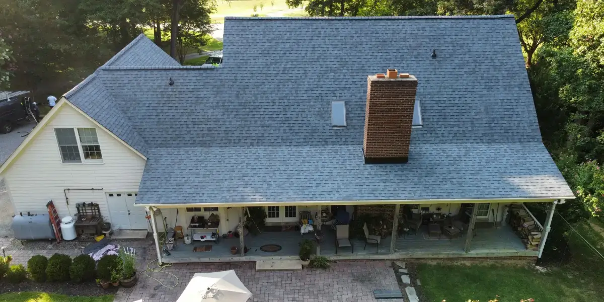 JDH Remodeling aerial view of a Mechanicsville Maryland home with blue-gray roof and brick chimney showing wear before full reroof in the Chopticon catchment