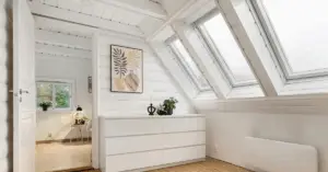 Modern fixed skylight installation in a bright attic bedroom with white shiplap walls.
