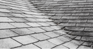 Close-up view of asphalt shingles curling and cracking, a clear sign of aging roof failure.