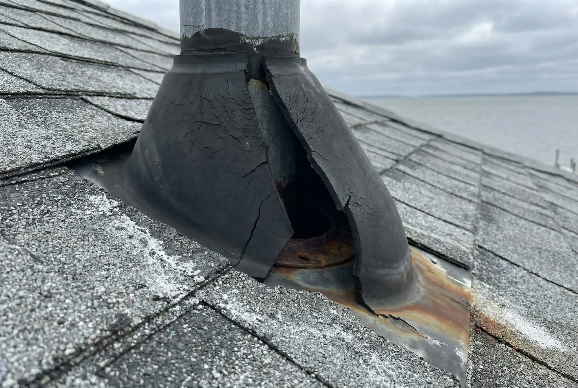 Cracked neoprene pipe boot on a Chesapeake Beach Maryland roof showing accelerated UV and salt air degradation
